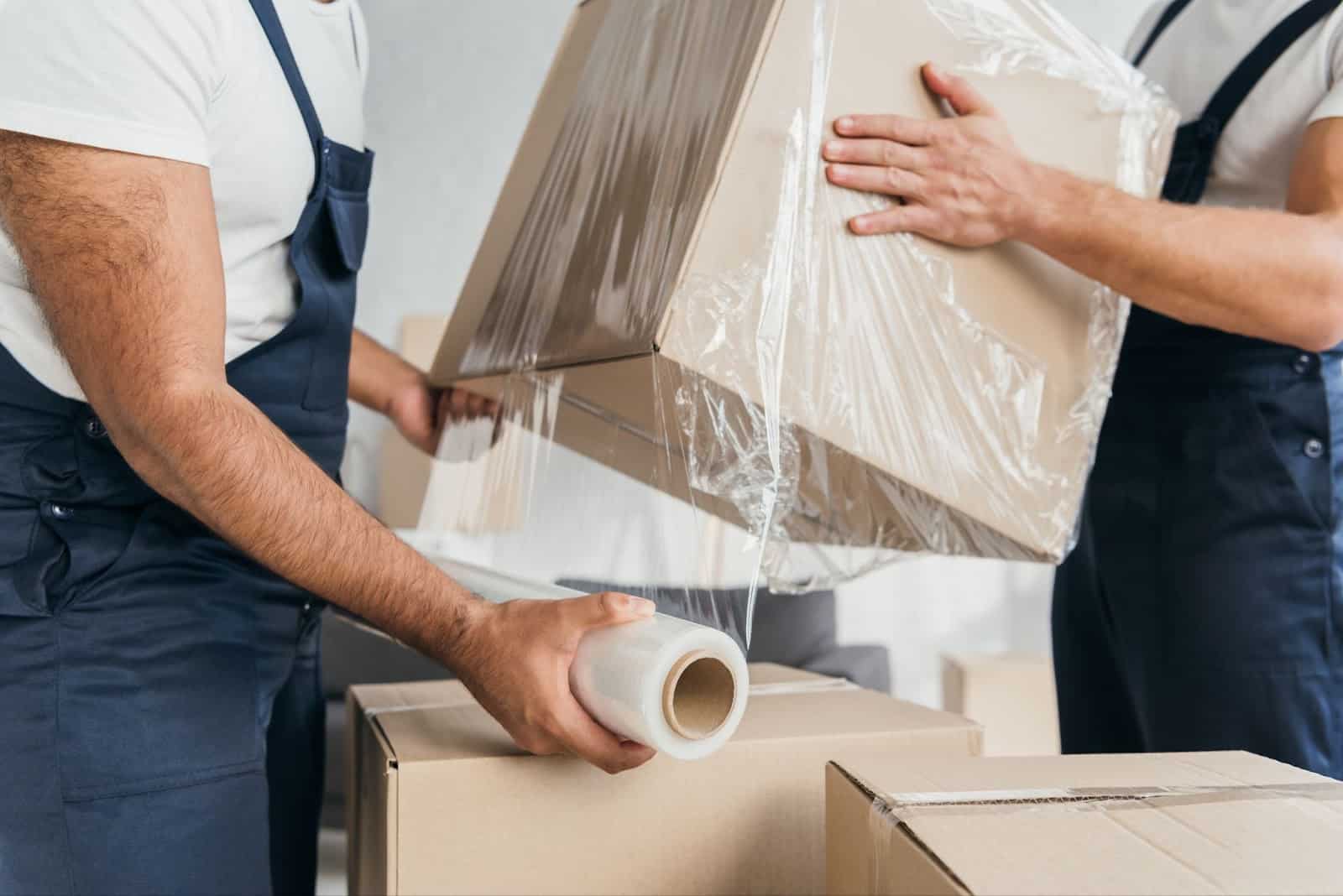 Flyttearbeidere pakker inn esker med plastfolie for beskyttelse